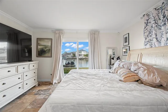 a bedroom with a bed a mirror on dresser and a flat screen tv