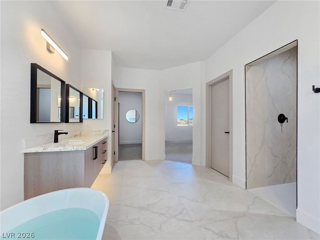 1120 West Gamebird Road Pahrump, NV 89048 - Photo 33 of 36 Bathroom featuring double vanity, a freestanding tub, light marble finish flooring, and a marble finish shower