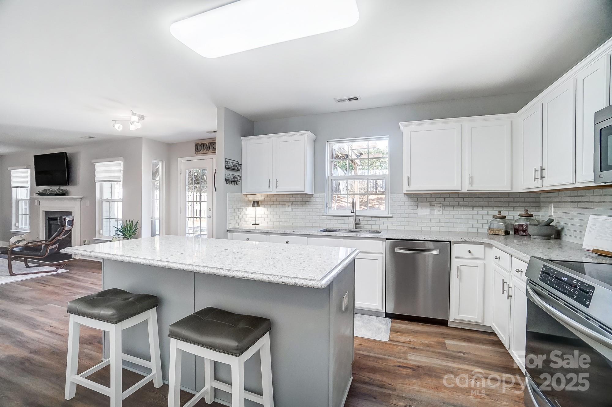 7647 Black Hawk Lane Tega Cay, SC 29708 - Photo 15 of 42 a kitchen with stainless steel appliances granite countertop a stove top oven a sink dishwasher and white cabinets with wooden floor