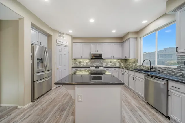 a kitchen with granite countertop a refrigerator sink and wooden cabinets