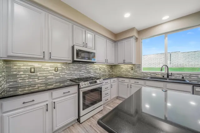 a kitchen with stainless steel appliances granite countertop a sink a stove and cabinets