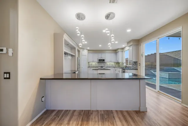 a large kitchen with stainless steel appliances a large counter top a stove and a refrigerator