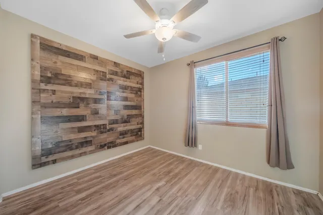 a view of an empty room with a window and wooden floor