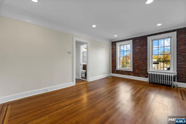 a view of an empty room with wooden floor and glass door
