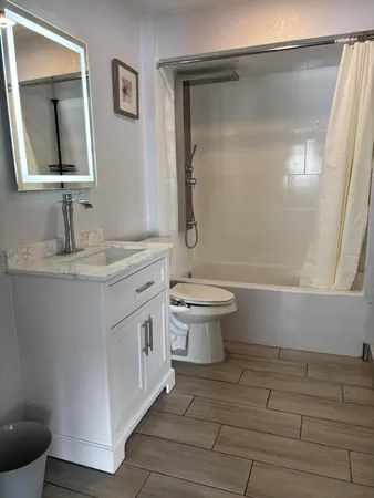 a bathroom with a granite countertop sink toilet and mirror