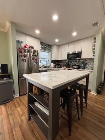 a kitchen with kitchen island a wooden floor and white cabinets