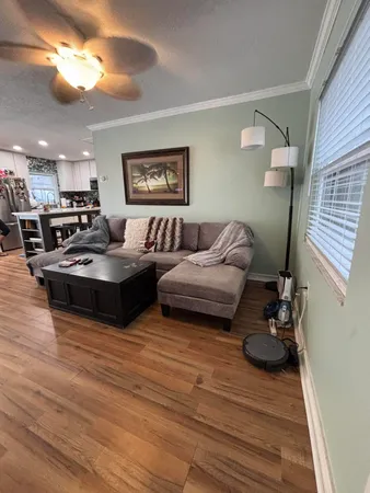 a living room with couches and kitchen view with wooden floor