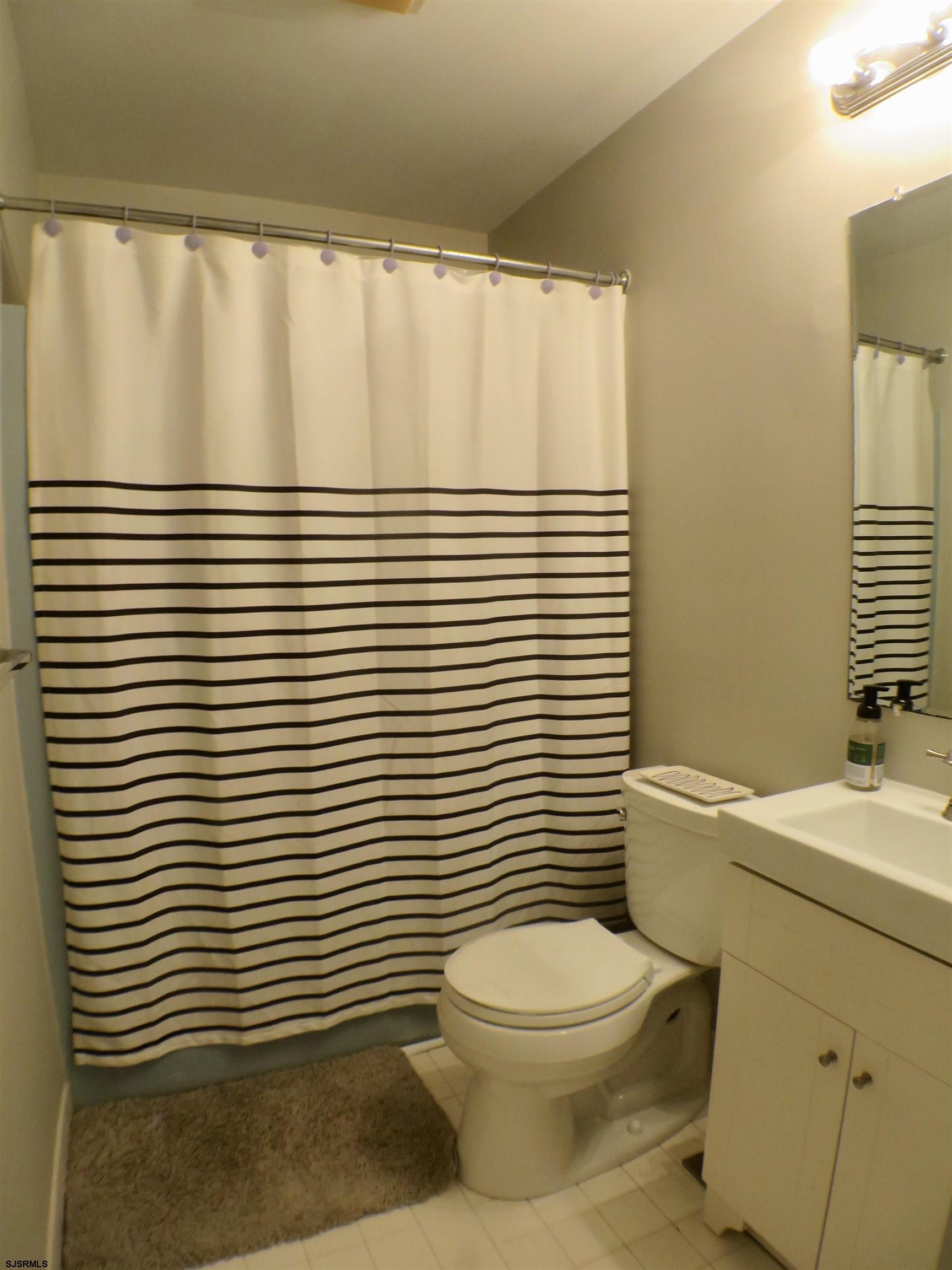 210 Simpson Avenue, Unit 2 Ocean City, NJ 08226 - Photo 17 of 20 a bathroom with a sink a toilet and shower curtain