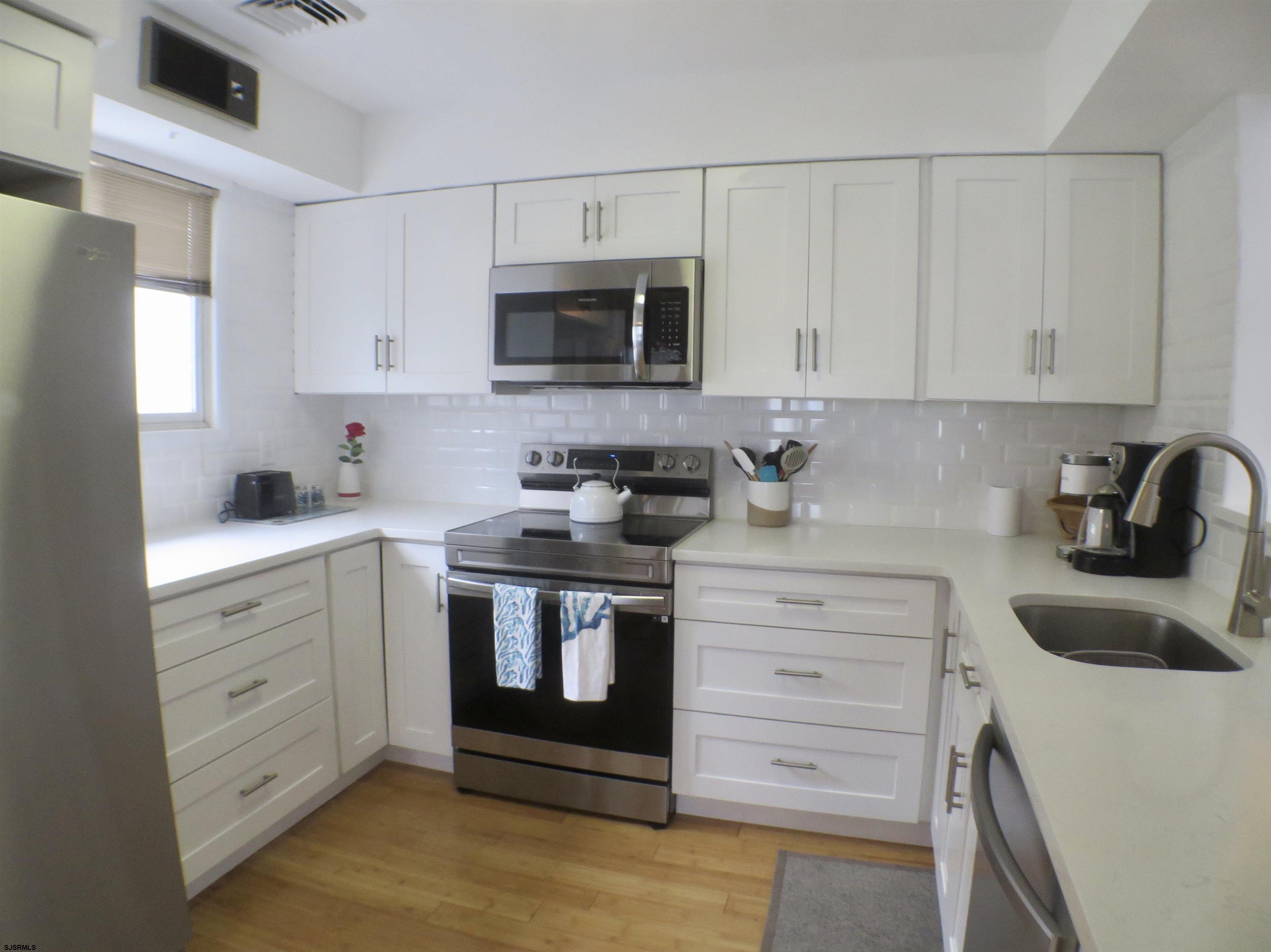 210 Simpson Avenue, Unit 2 Ocean City, NJ 08226 - Photo 8 of 20 a kitchen with white cabinets and stainless steel appliances