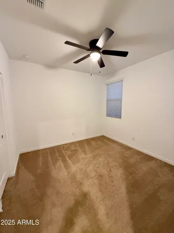an empty room with a ceiling fan and carpet