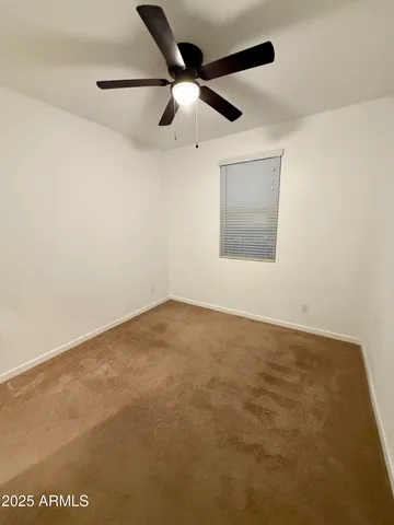 an empty room with a ceiling fan and a window