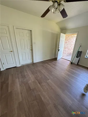 an empty room with wooden floor fan and windows