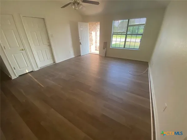 an empty room with wooden floor and windows