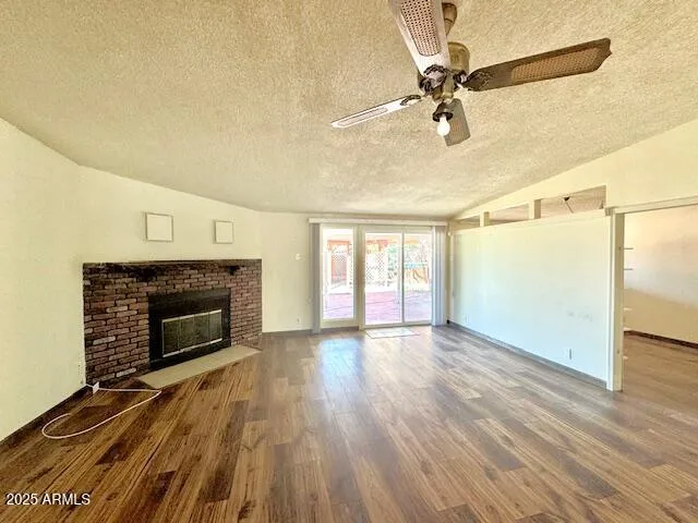 a view of an empty room with wooden floor fireplace and a window