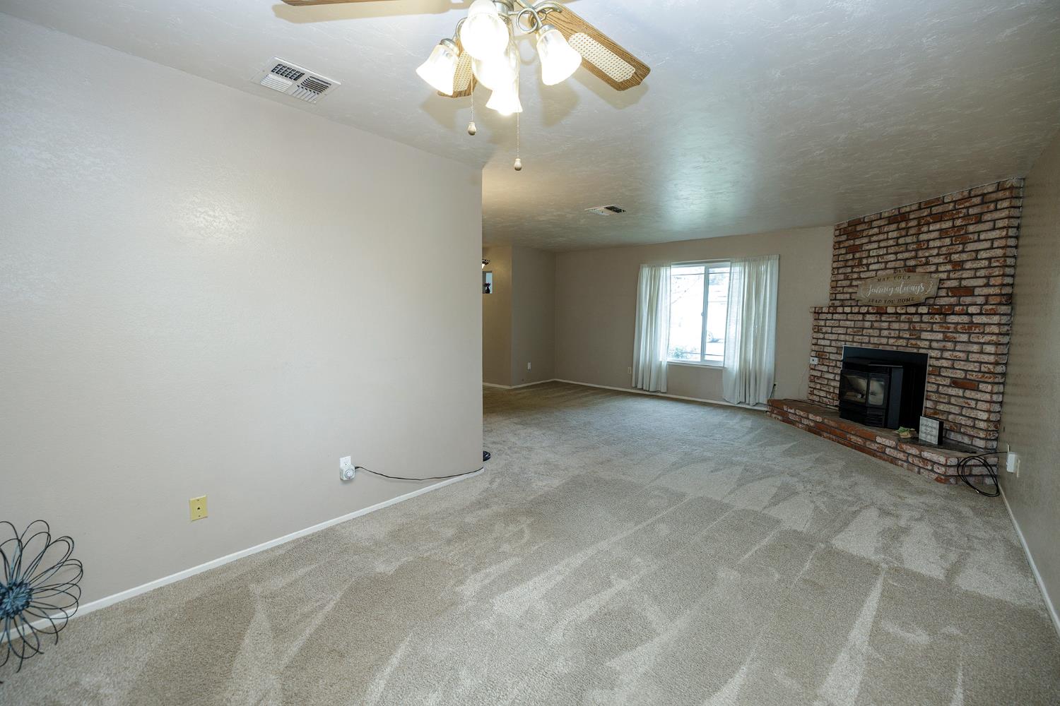 495 Valdapena Way Escalon, CA 95320 - Photo 12 of 43 an empty room with a fireplace and fan