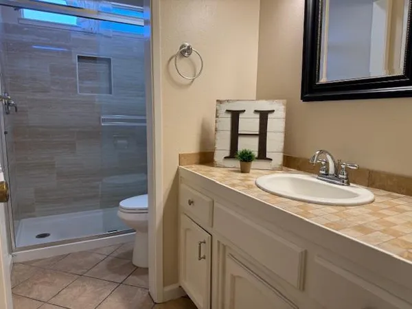 a bathroom with a granite countertop sink a toilet and a mirror