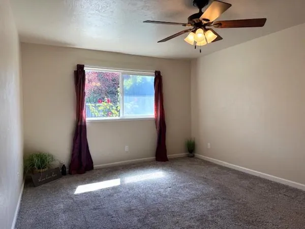 an empty room with windows and fan