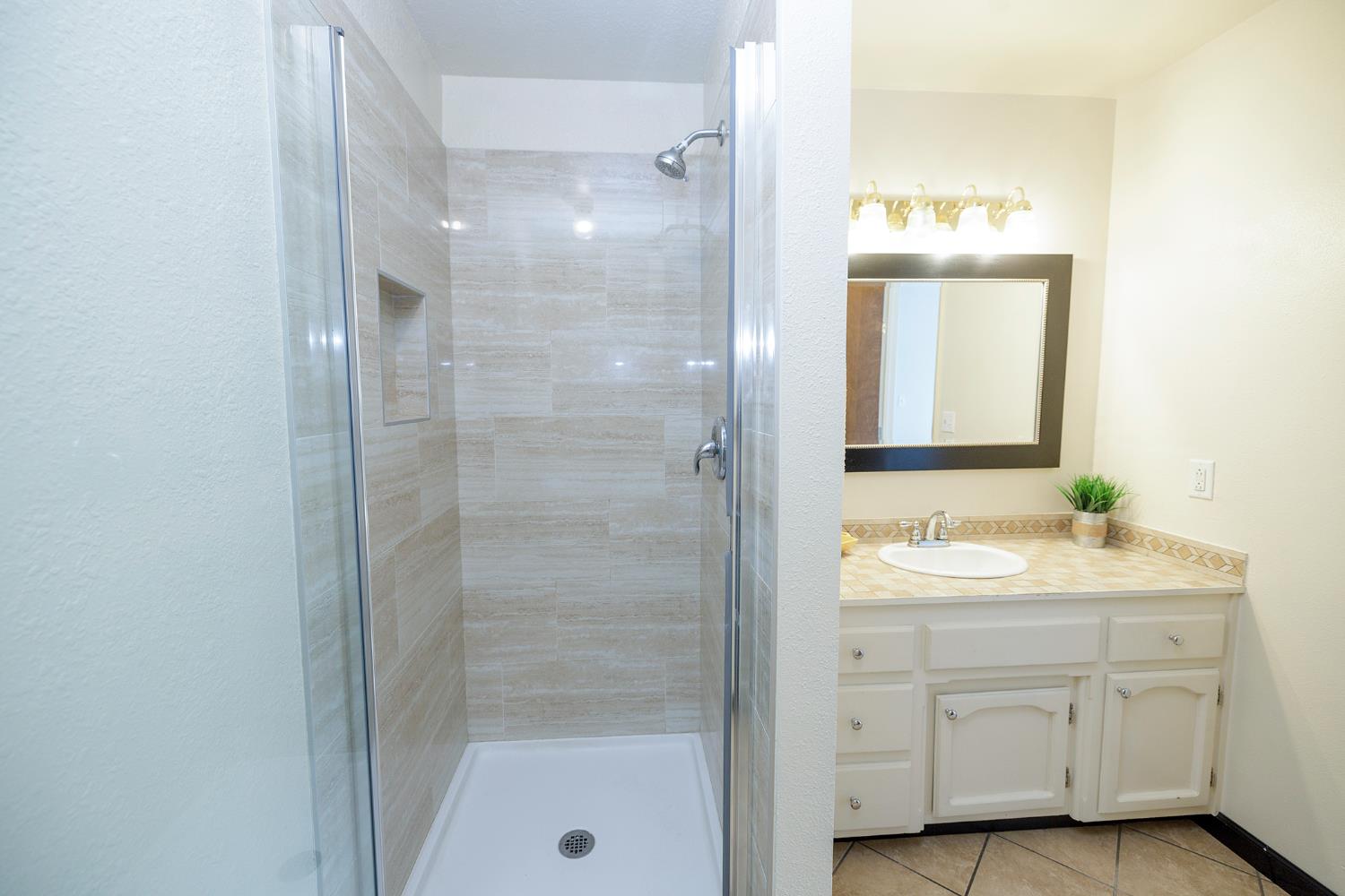 495 Valdapena Way Escalon, CA 95320 - Photo 24 of 43 a bathroom with a shower sink and mirror