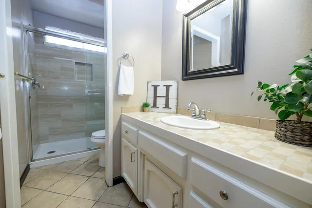 a bathroom with a granite countertop sink a mirror and a shower