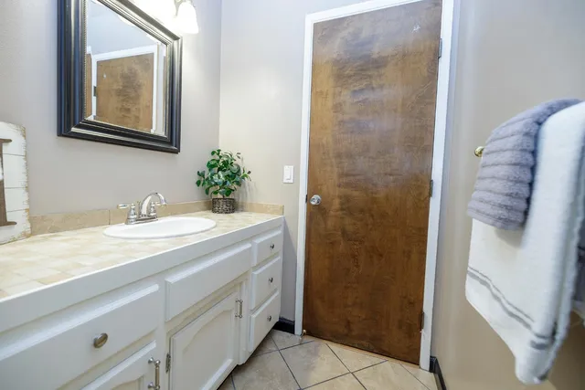 a bathroom with a granite countertop sink a mirror and a shower