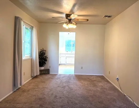 an empty room that has a window and a ceiling fan