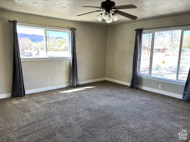 247 West 400 North, Unit 1 Moab, UT 84532 - Photo 8 of 27 Spare room with dark colored carpet, ceiling fan, and a textured ceiling