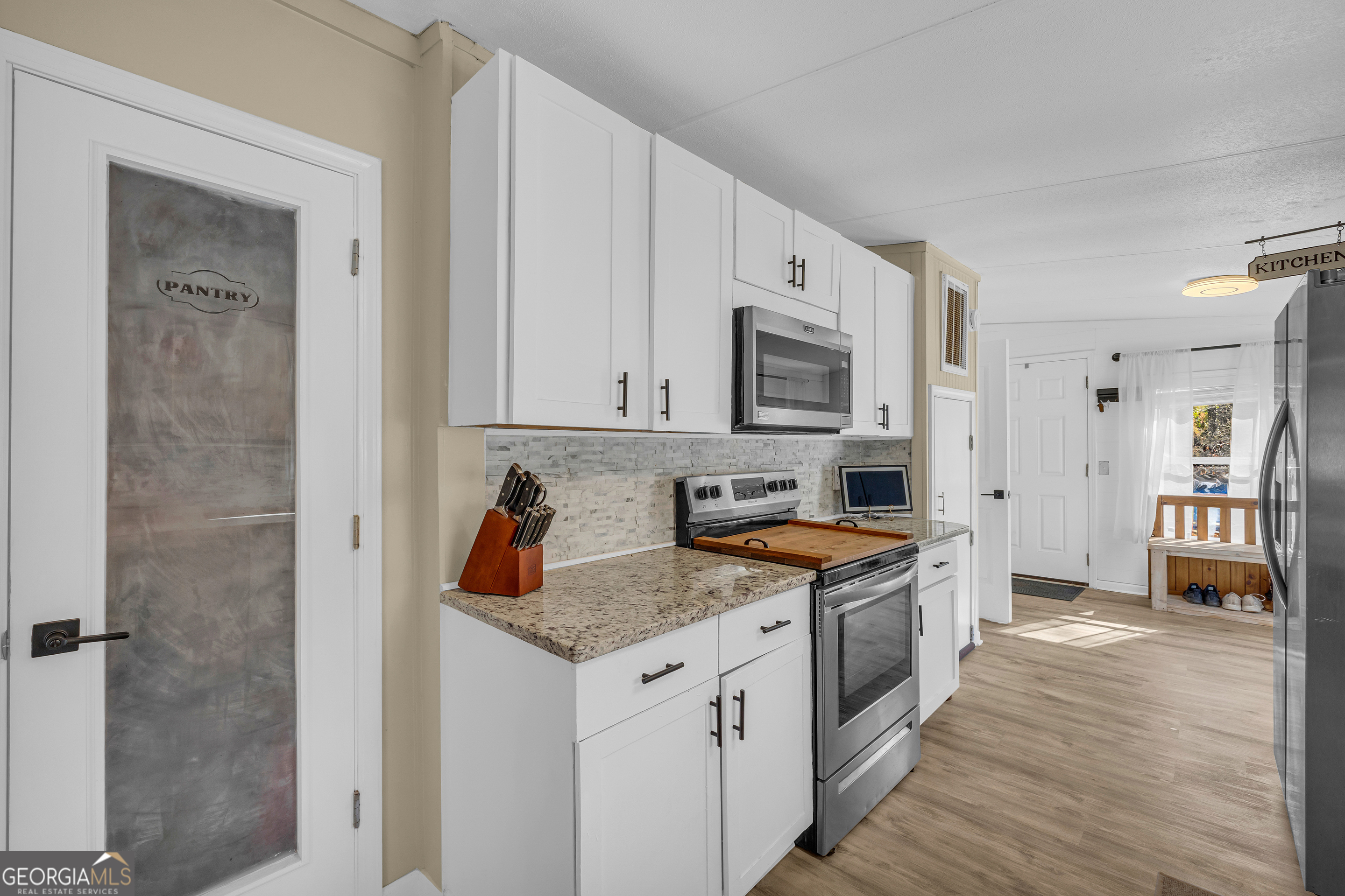 3656 Candler Road Pendergrass, GA 30567 - Photo 22 of 34 a kitchen with stainless steel appliances granite countertop a stove top oven a sink a refrigerator white cabinets and wooden floor