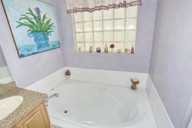 a bathroom with a granite countertop sink and a bathtub