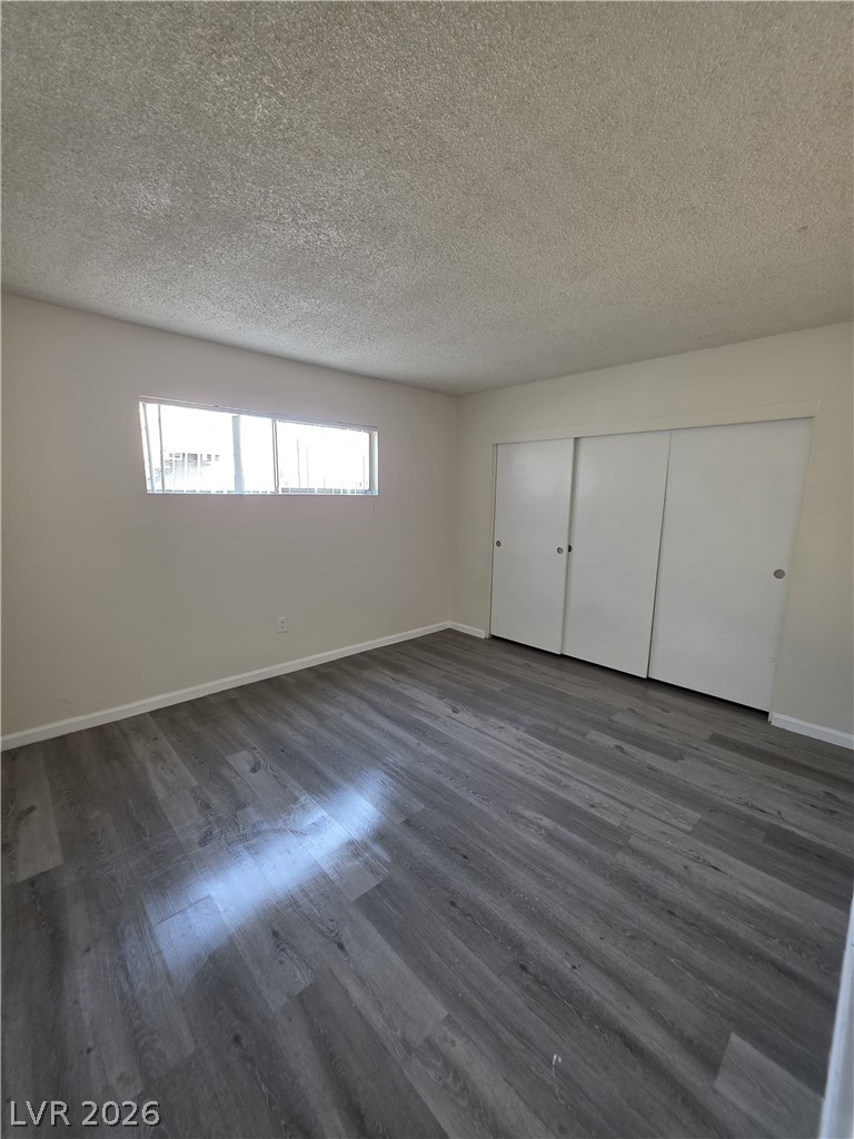 1075 East Desert Inn Road, Unit 5 Las Vegas, NV 89109 - Photo 2 of 12 Newly installed laminate flooring enhances this spacious and well-lit bedroom.