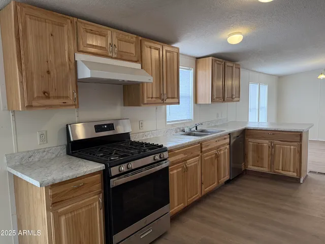 a kitchen with granite countertop a stove cabinets and wooden floor