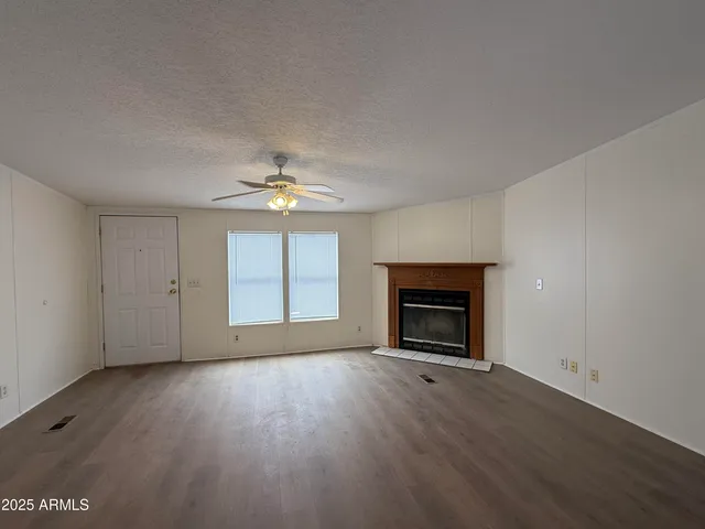 an empty room with windows fireplace and wooden floor
