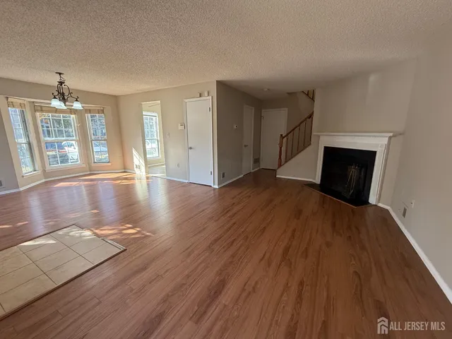 an empty room with wooden floor fireplace and windows