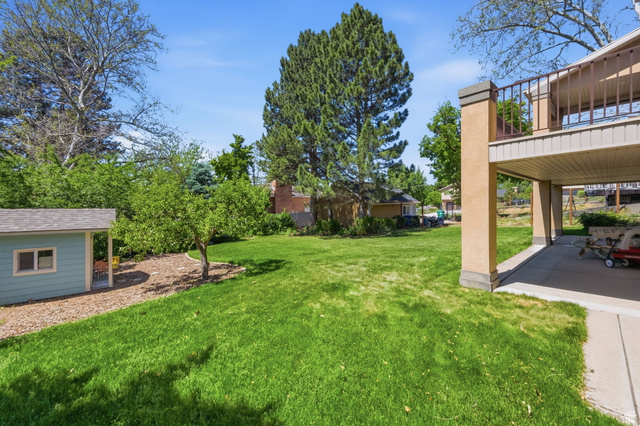 1683 North Main Street Centerville, UT 84014 - Photo 34 of 37 Expansive backyard featuring a lush lawn, mature trees, a dedicated shed, and a covered patio area
