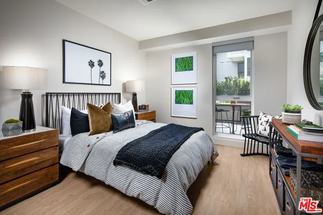 a bedroom with bed a flat tv screen and a dresser next to a window