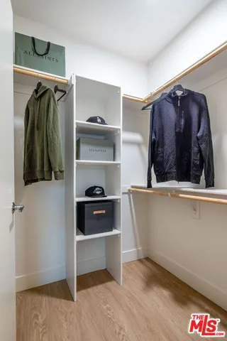 a view of walk in closet with clothes and shoes
