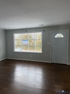 an empty room with wooden floor and windows