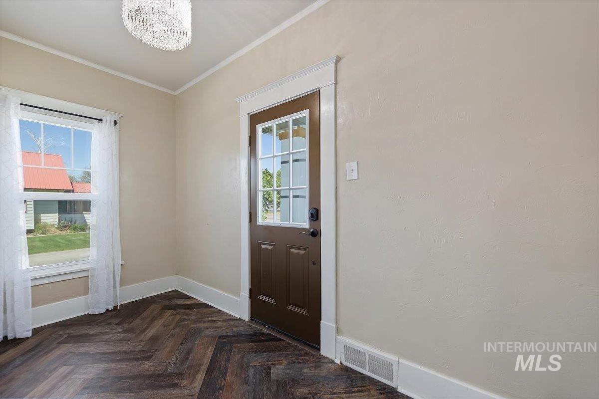 813 7th Street Rupert, ID 83350 - Photo 6 of 48 Entry area featuring wood-finish flooring in a herringbone pattern, a brown paneled door with glass inserts, and a window with white trim