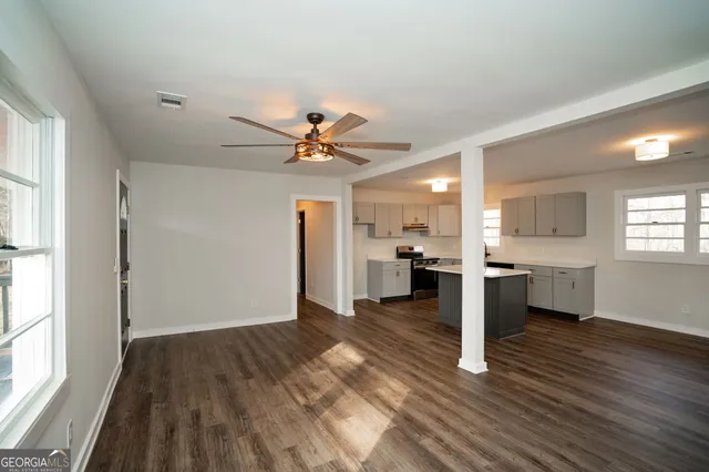 a kitchen with stainless steel appliances granite countertop a refrigerator a sink dishwasher a stove and white countertops with wooden floor