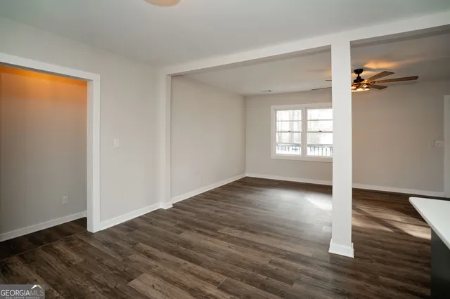 an empty room with wooden floor chandelier and windows