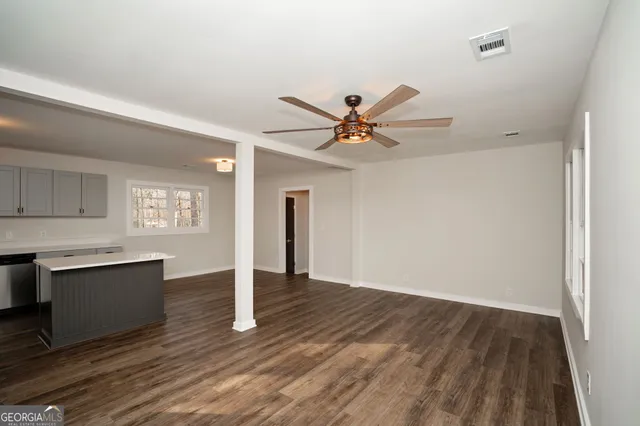 an empty room with wooden floor a ceiling fan and windows