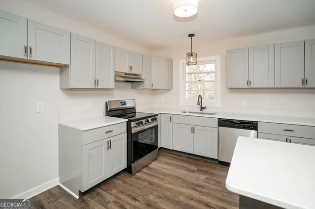 a view of an empty room with wooden floor and a ceiling fan