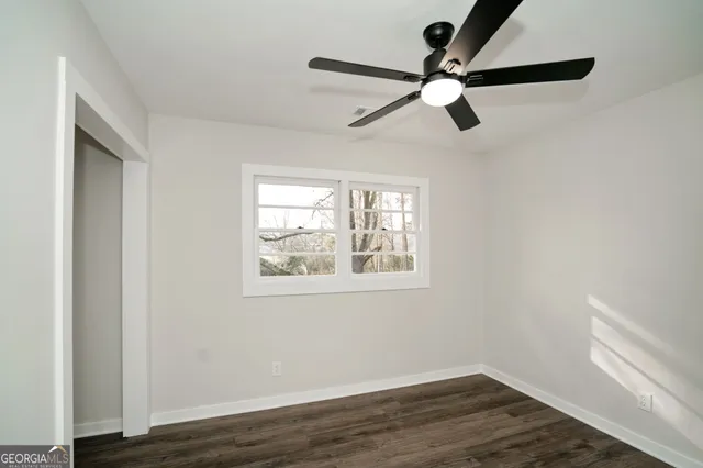 an empty room with wooden floor a ceiling fan and windows