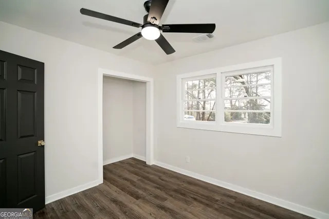 a view of empty room with wooden floor and fan
