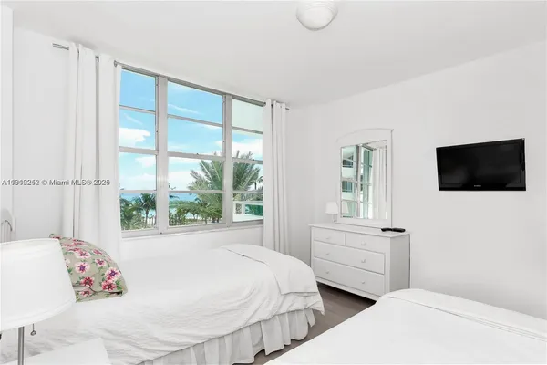 a bedroom with a bed and a flat tv screen on the dresser