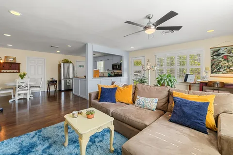 a living room with furniture kitchen view and a large window