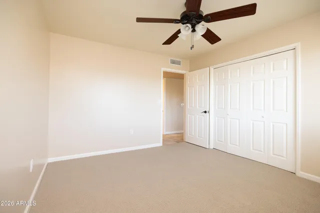 an empty room with a ceiling fan and carpet