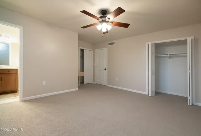 an empty room with closet and a ceiling fan
