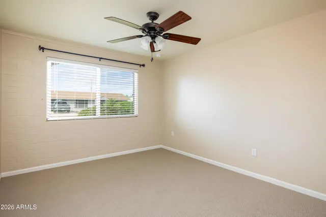 an empty room with a window and a fan