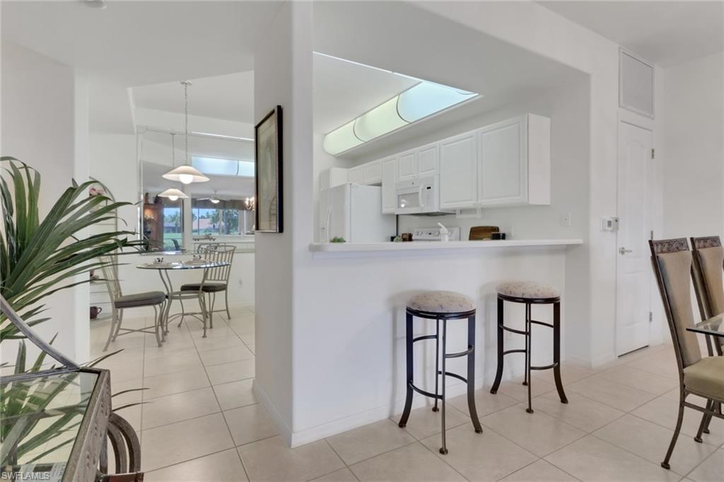 23790 Clear Spring Court, Unit 1603 Estero, FL 34135 - Photo 5 of 39 a kitchen with stainless steel appliances kitchen island granite countertop a table chairs and a refrigerator