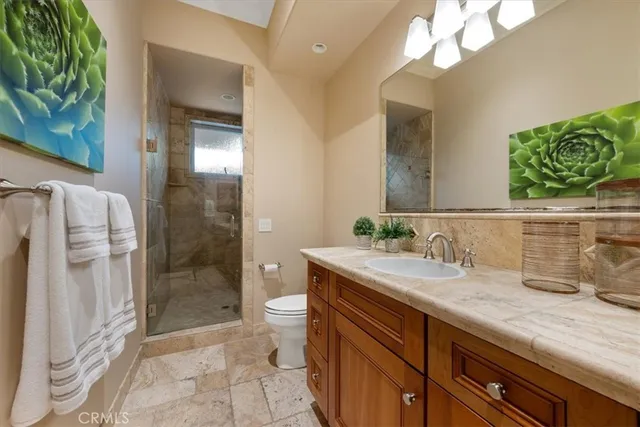 a bathroom with a granite countertop sink a toilet a shower and mirror